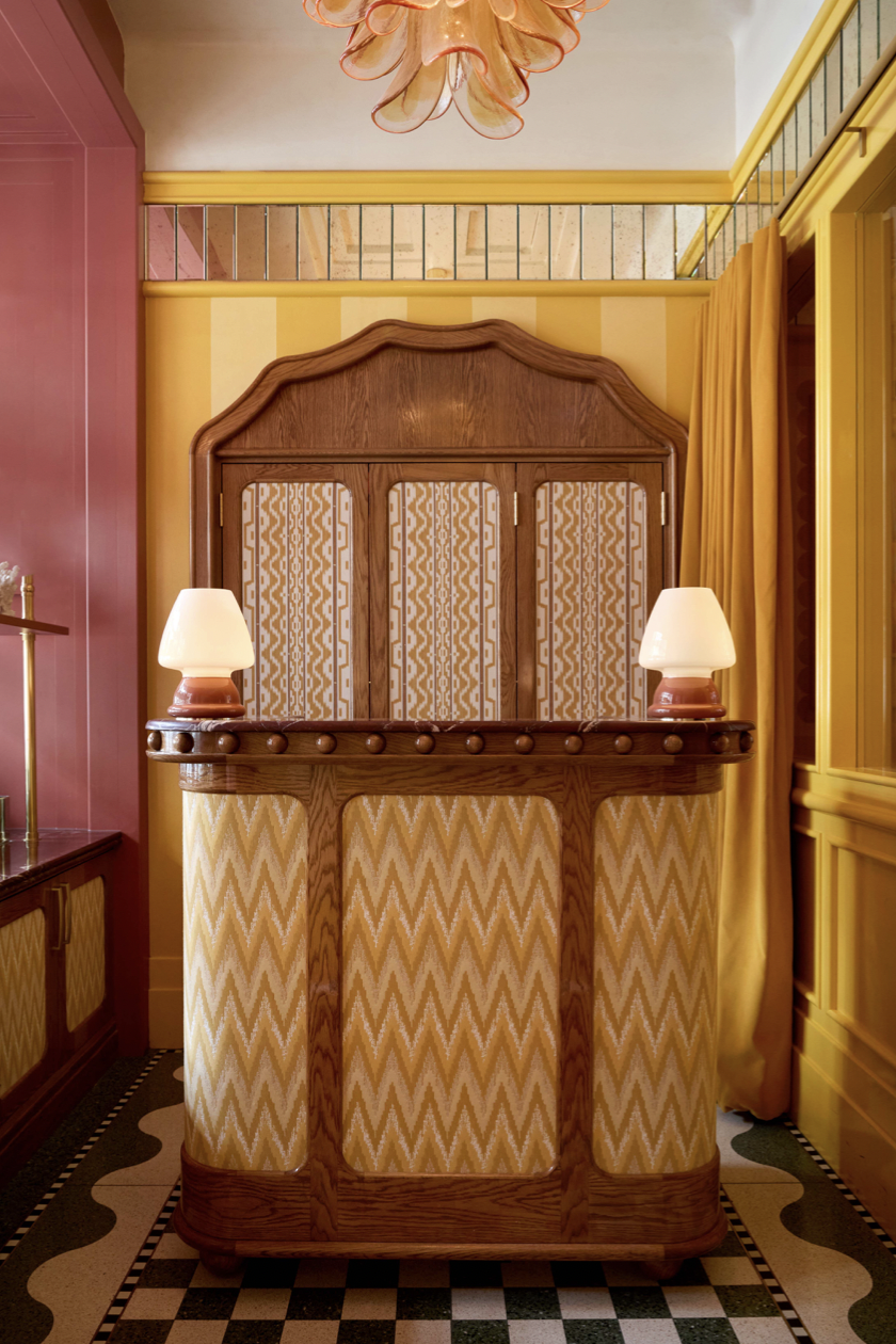 A wood and '70s mustard striped reception desk, flanked by two squat lamps