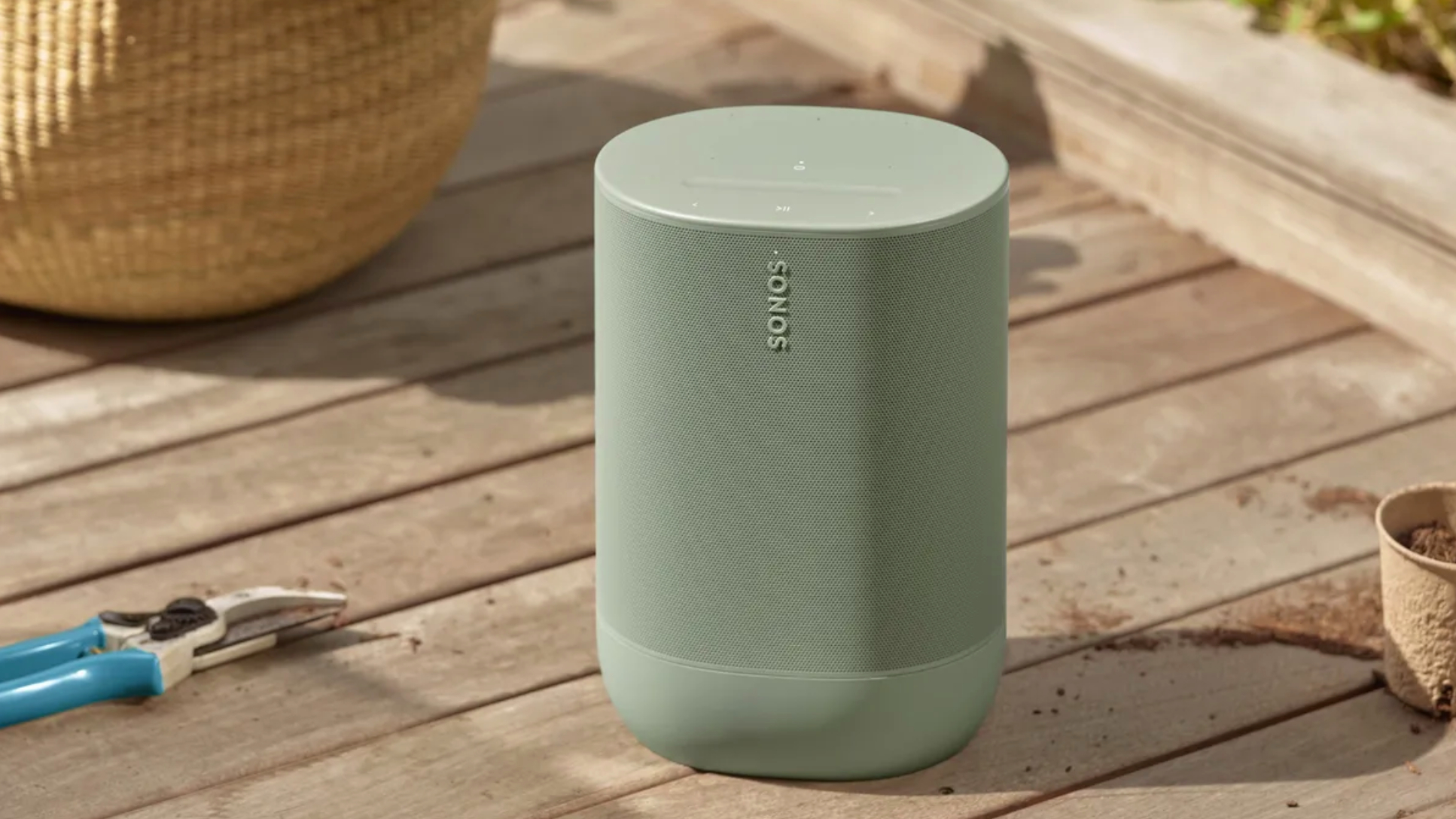 An olive green Sonos speaker on wooden decking