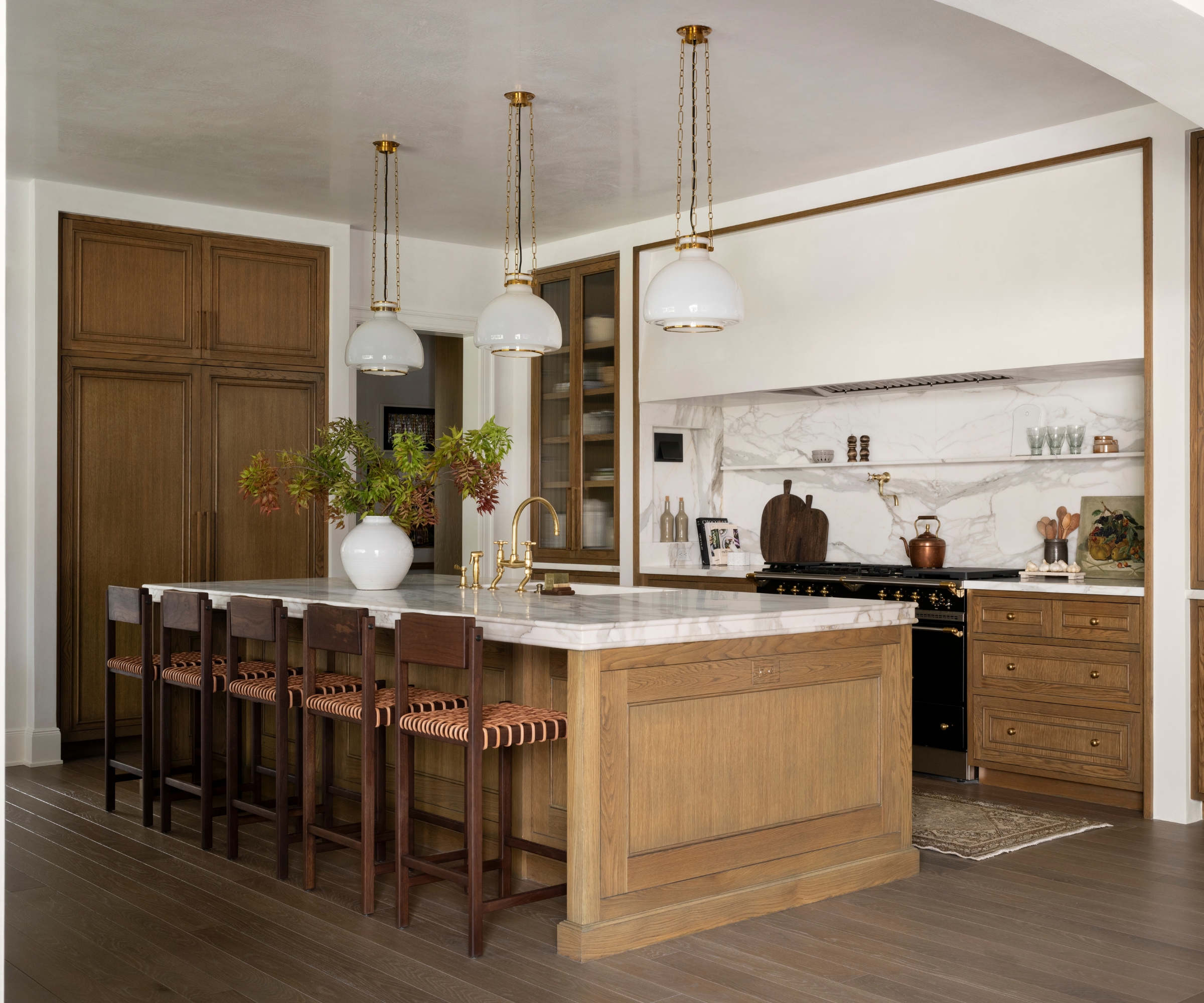 A large kitchen with rich wood cabinets, white walls, and marble countertops