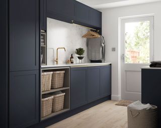 A navy utility room with a wooden floor and wicker baskets.