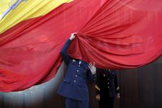 A member of the Spanish Armed Forces gets his face covered by a giant Spanish flag as he helps raise it during a ceremony to mark the 37th anniversary of the 1978 Spanish constitution in Madr
