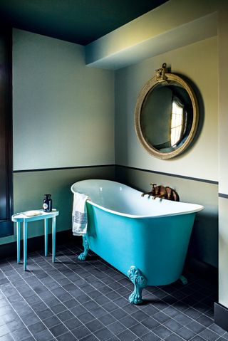 Bathroom with turquoise bath and dark gray floor tiles
