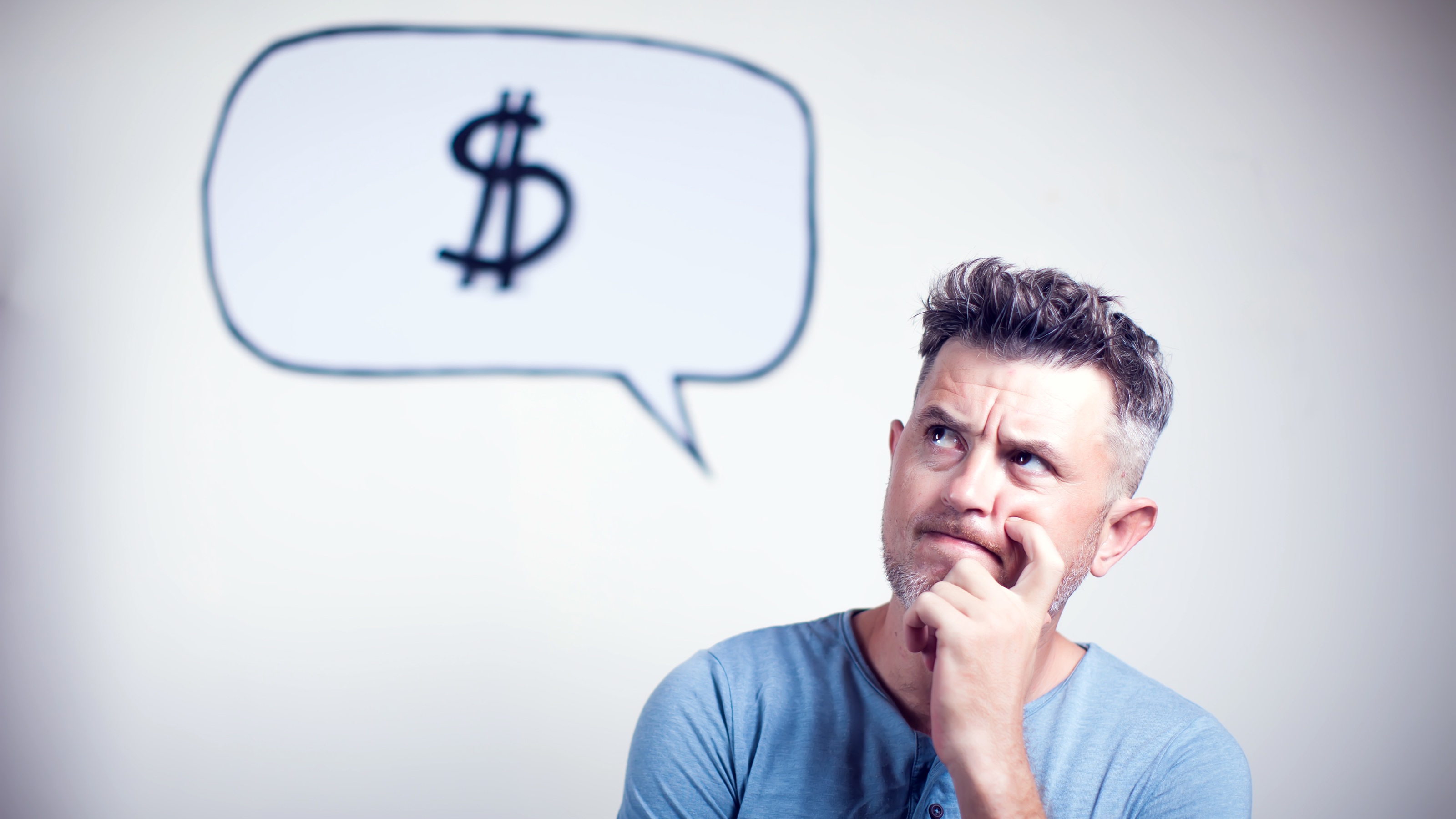 A man appears to be thinking and has a thought bubble above of his head with a dollar sign in it.