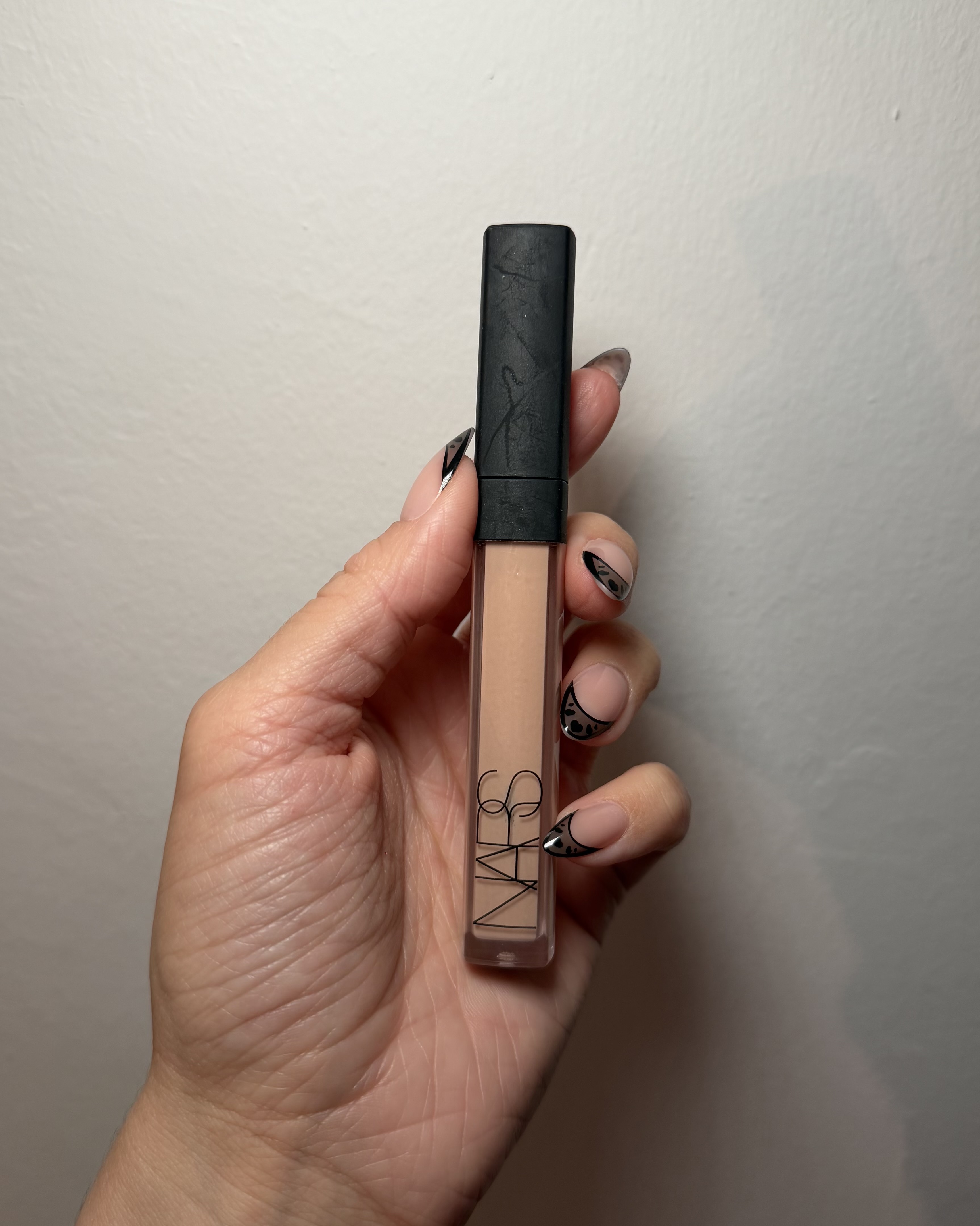 An image ofBest Knockoff Luxury Clothing
 associate beauty editor Alyssa Brascia wearing and holding the Nars Radiant Creamy Concealer.