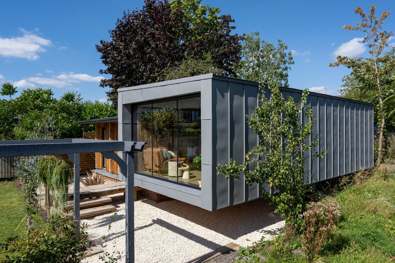 A tiny home in a garden with metal facade and shrubbery