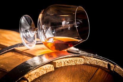 Glass of cognac on the old wooden barrel