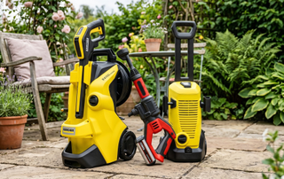 Three of the best pressure washers on a patio with plants and garden chair in background