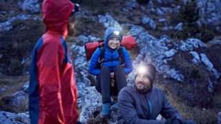 Smiling mountaineers wearing headlamps in the mountains at dusk