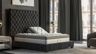 The Saatva Solaire Upper Flex queen mattress in a luxury bedroom with one side of the bed raised