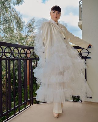 Devery Jacobs on the balcony of her Emmys getting ready hotel room wearing a tulle suit