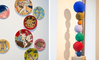 Colourful plates displayed on a wall and a stack of different coloured and sized balls on a podium