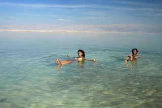 Two young women floating on back in Dead Sea The unusual buoyancy caused by high salinity
