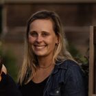 Head shot of May Zegarelli, co-founder of Ocean Fog Farm, wearing a denim shirt, taken outdoors with greenery and fencing in the background