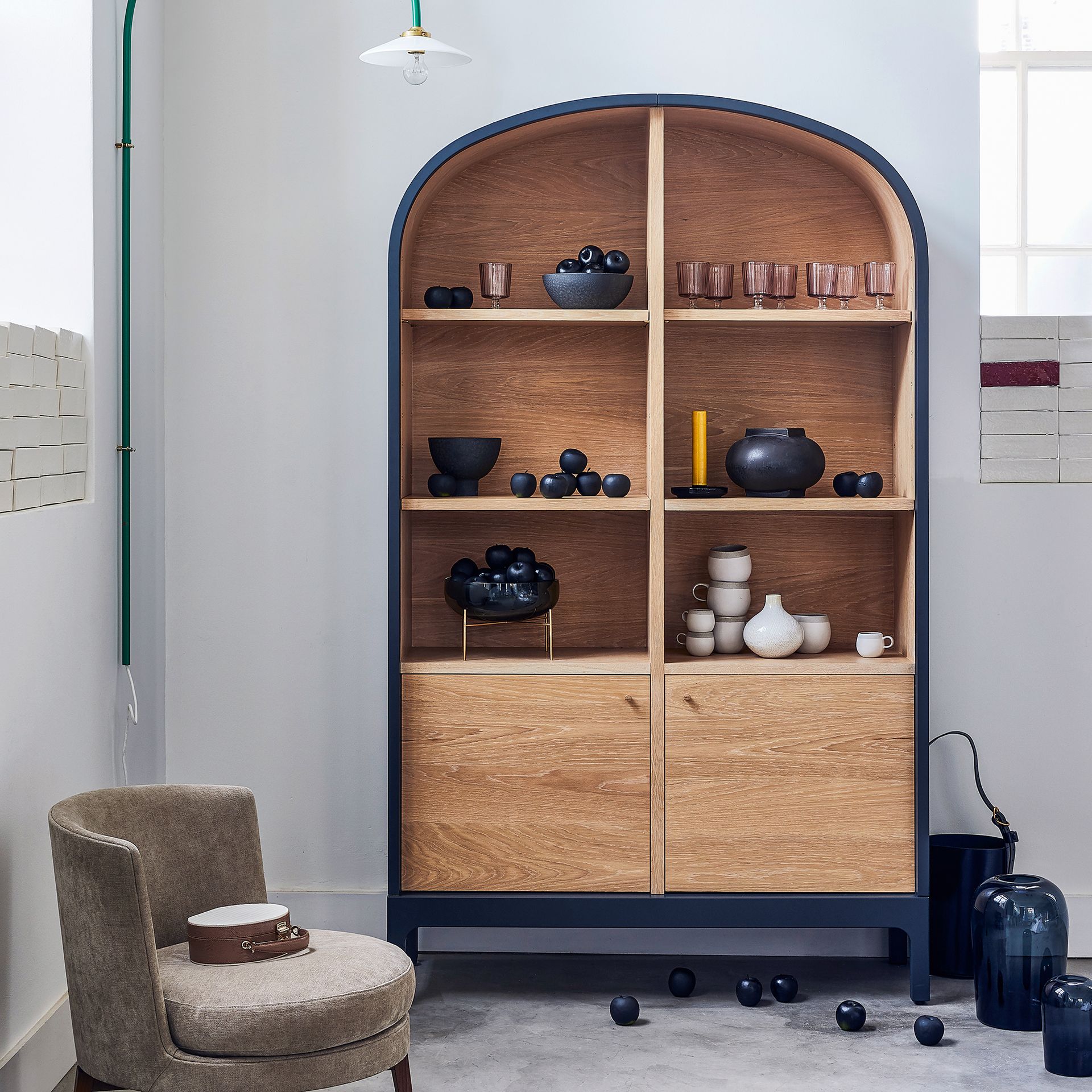 Curved wooden cabinet beside round armchair