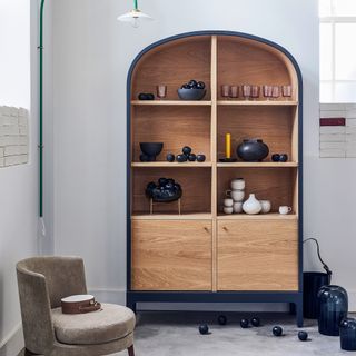 Curved wooden cabinet beside round armchair