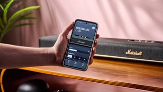 Person holding out phone with Marshall app in front of the Marshall Heston 120