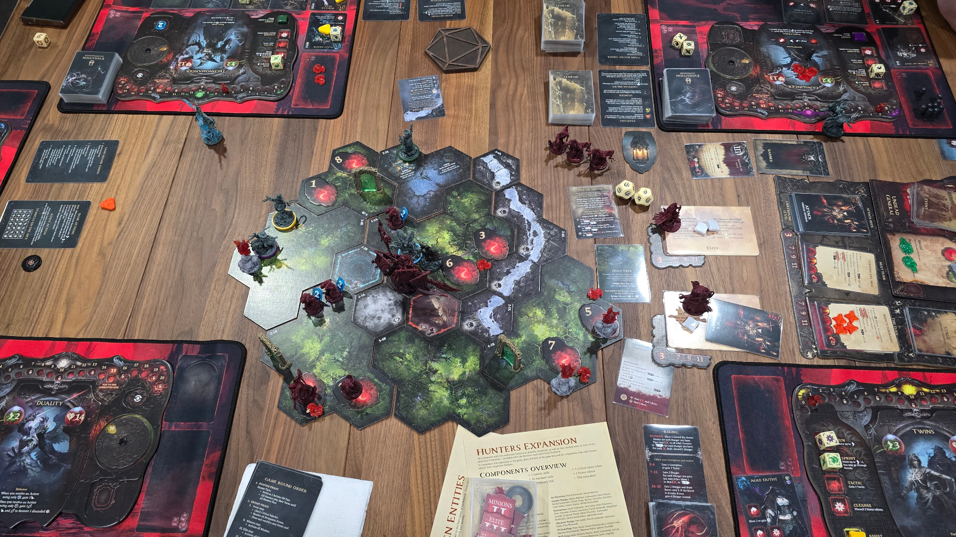 Grimcoven board tiles, miniatures, cards, and tokens laid out on a wooden table