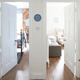 room with white door wooden flooring and sofa sets