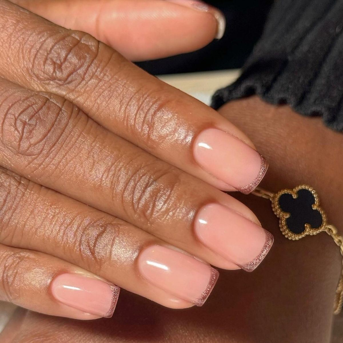 A short, square, brown, cat-eye French tip manicure