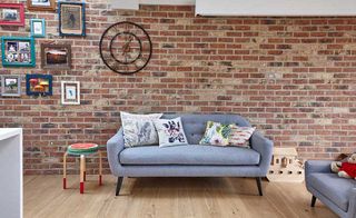 grey sofa exposed brick wall in a kitchen diner