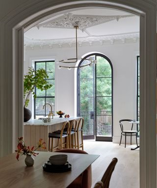 A kitchen with an island, high ceilings and a large arched doorway
