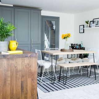 dining area with white wall grey cabinets and white floor