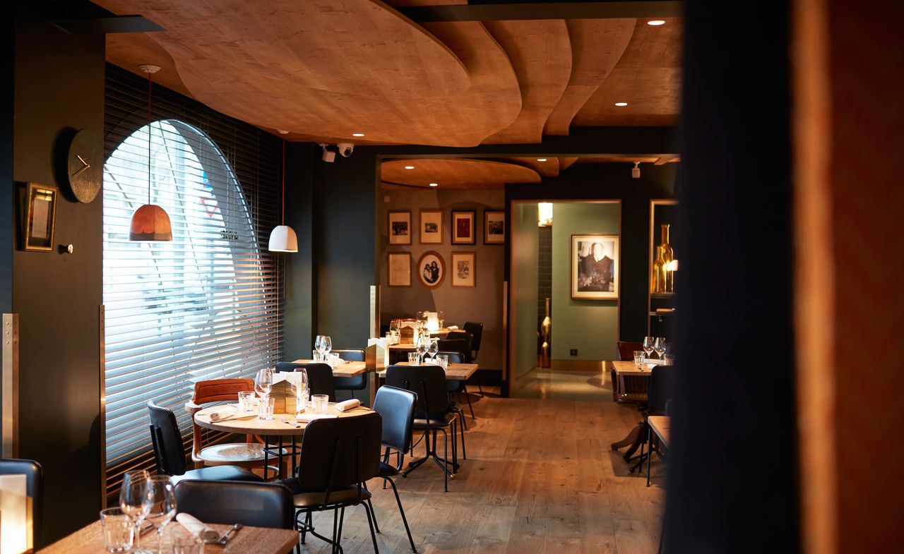 Dining area with wooden tables and dark, leather chairs. Dining area with wooden tables and dark, leather chairs below a stepped, wooden ceiling