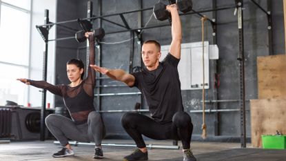 Pair perform a dumbbell squat simultaneously