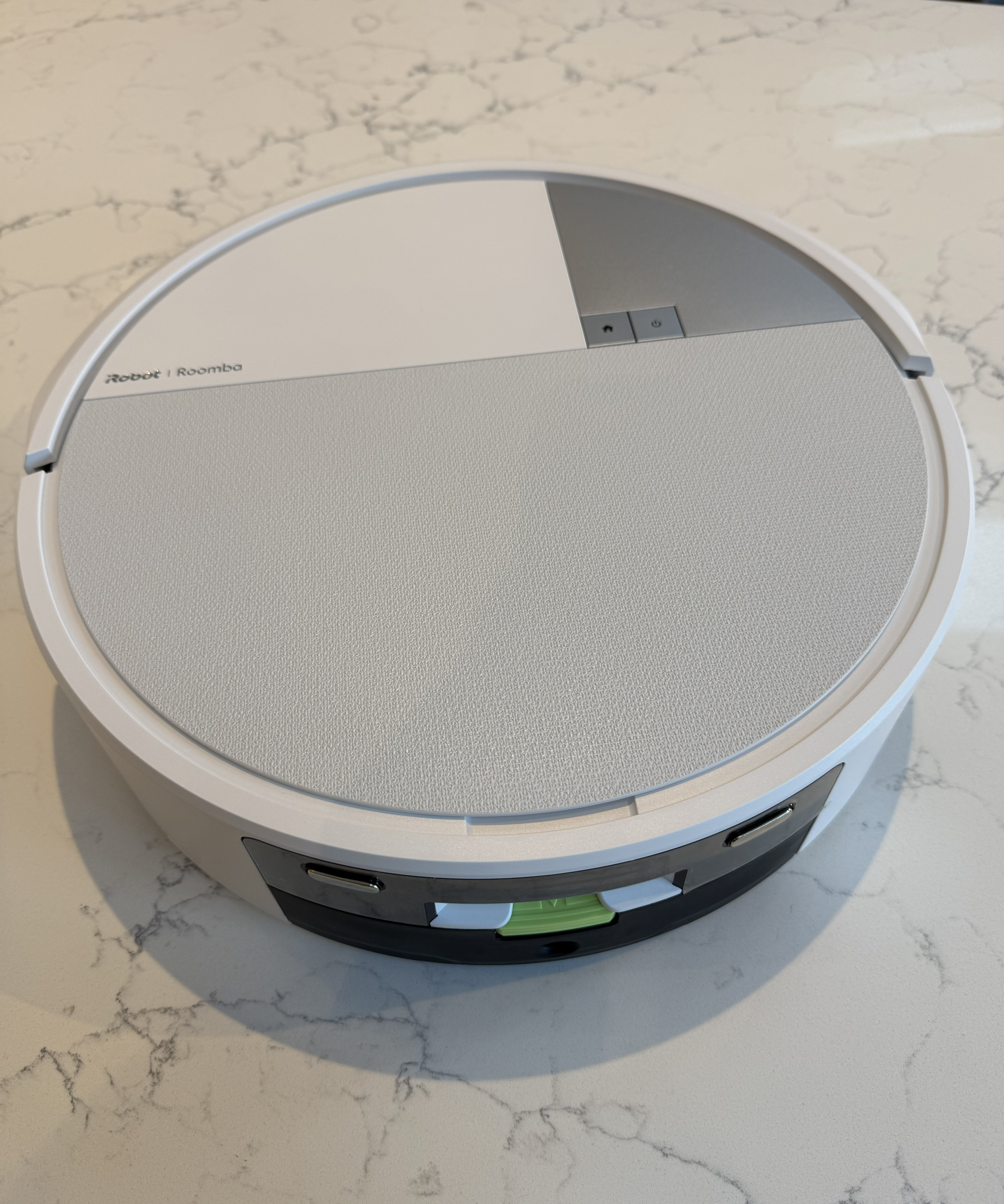 The top of the Roomba Max 705 is pictured where you can see the physical power and docking buttons and the small on-board water tank