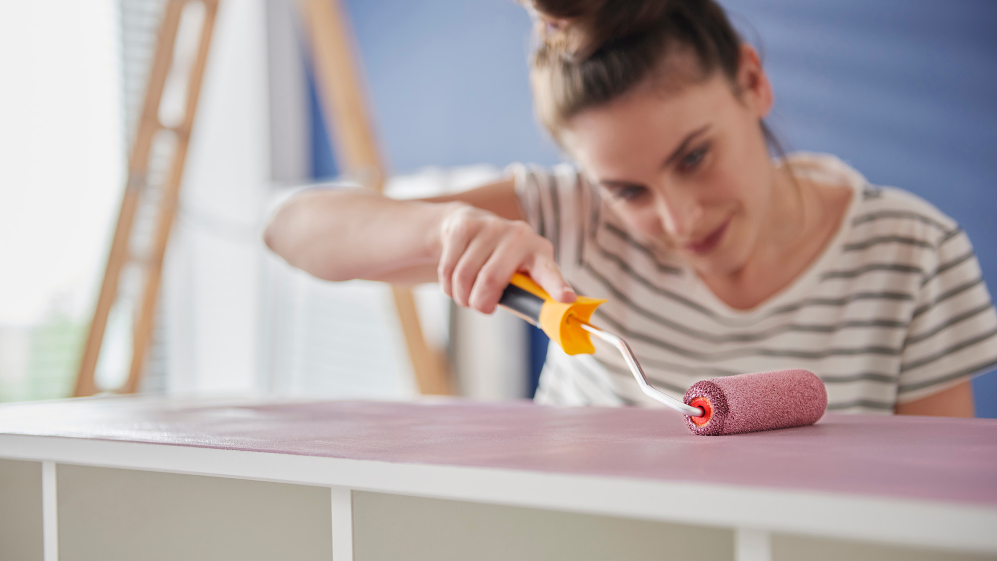 Woman painting shelving unit with a roller