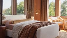 Bedroom with terracotta wall and cream bedframe with brown throw