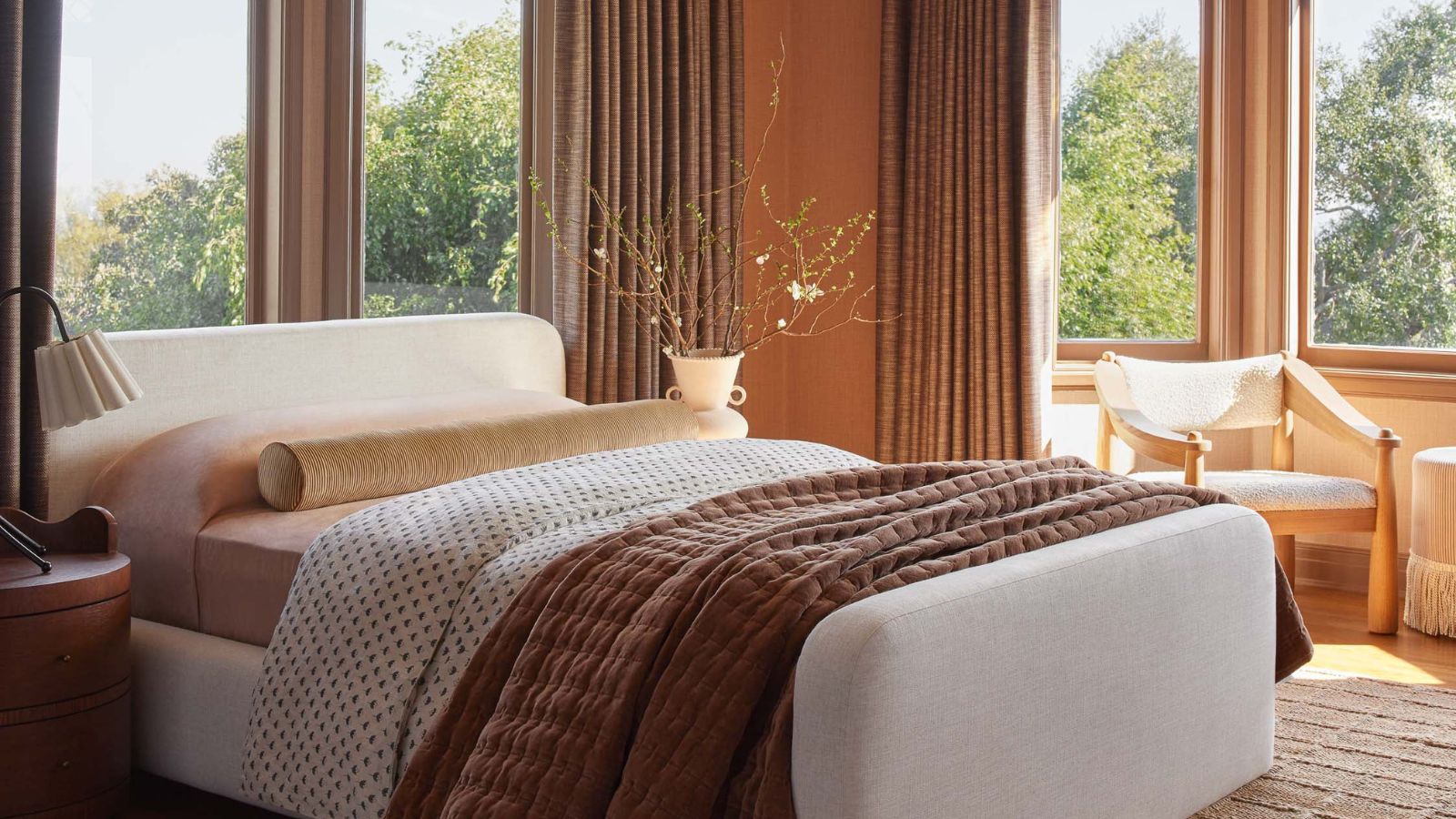 Bedroom with terracotta wall and cream bedframe with brown throw