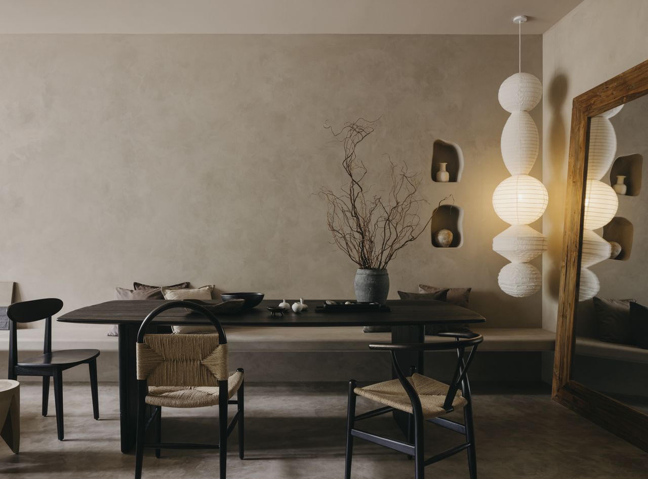 A dining room with an earthy aesthetic and a long, hanging lamp