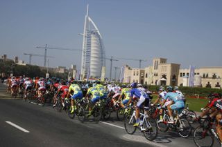 The peloton races against the Dubai skyline.