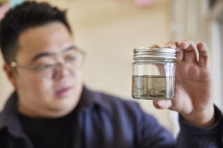 Hanson Cheng holding jar of liquid containing tyre wear particles