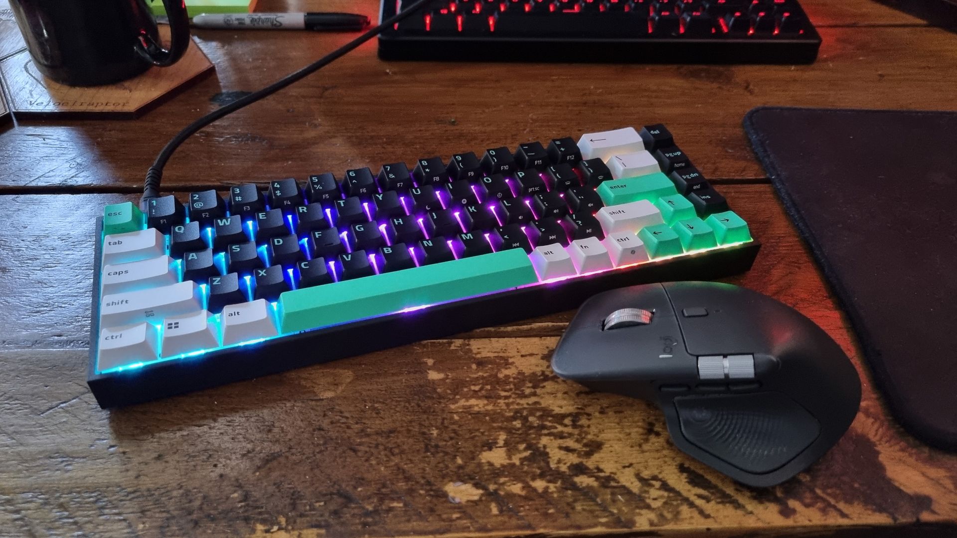 The Razer Reclusa X Mini 65% next to a Logitech MX Master 4 on a wooden desk