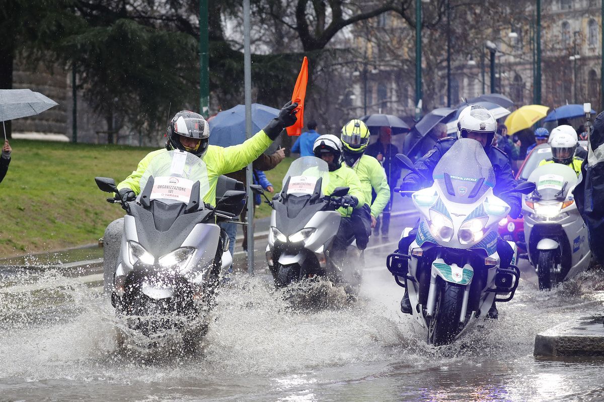 The lead motorcycles warn riders of puddles at the start of Milan-San Remo