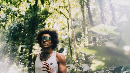 Best cycling sunglasses: Pictured here, an athletic person with a tattoo walking in a forest wearing the Tifosi Rail glasses