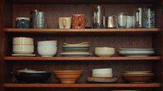 Wooden shelf with glasses and bowls on it