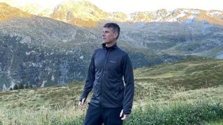 A man stands in the mountains wearing a black Columbia Park View Fleece