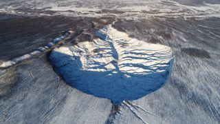 a huge frozen sinkkhole in an arid landscape in Siberia