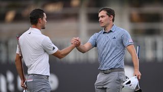 Nicolai Hojgaard (L) and Rasmus Hojgaard (R) of Denmark interact after finishing their round on the 18th green during Round Three of the Hero Dubai Desert Classic.