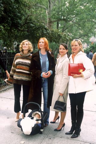 Kristin Davis as Charlotte York wearing a buttoned coat, balck pumps, and a black mini handbag