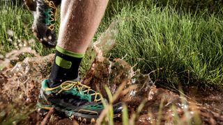 Feet of trail runner running through mud