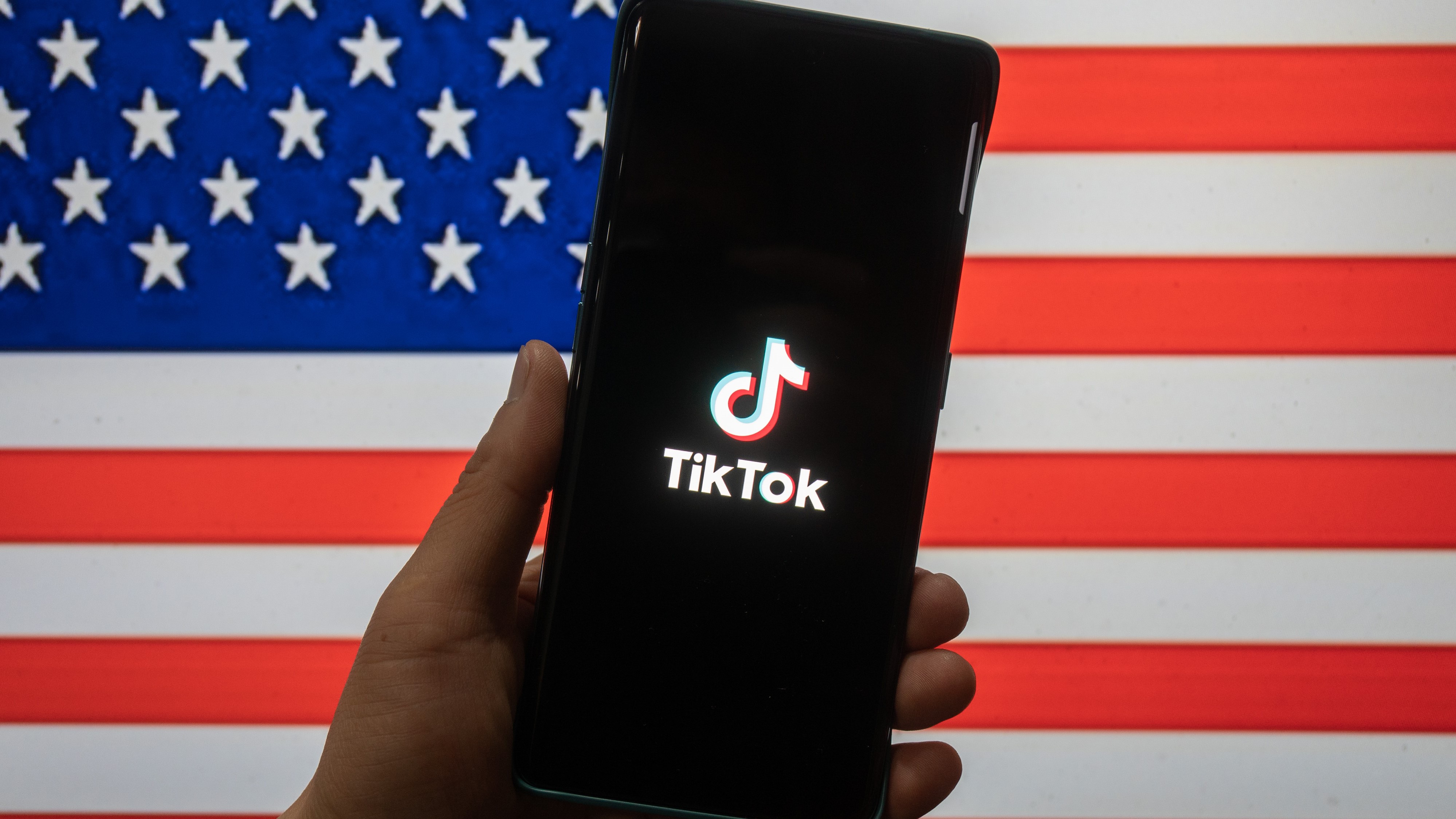 TikTok روی گوشی در مقابل پرچم ایالات متحده