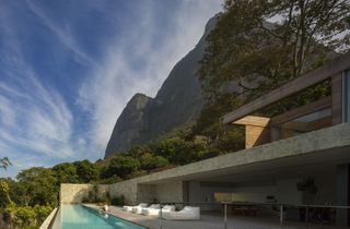 The house is nestled into the foothills of Pedra da Gávea, a 2,769 ft granite mountain