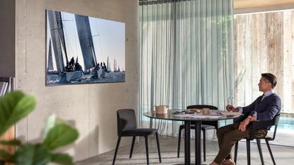 Samsung TV on wall while man watches from breakfast table