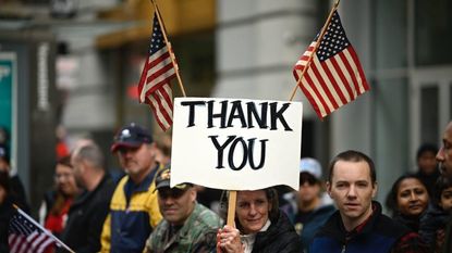 A woman holds a sign reading "Thank You" at a Veterans Day parade in New York City.