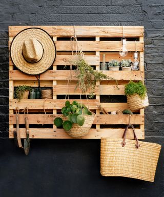 Wooden pallet. mounted on a wall with plant pots and garden tools
