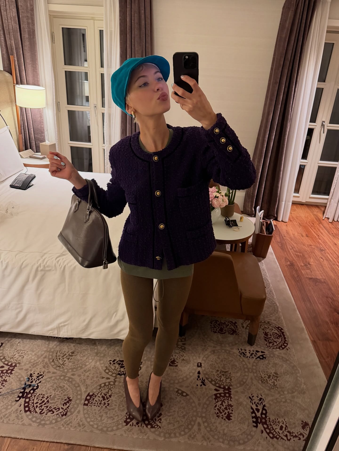 Iris Law takes a mirror selfie wearing khaki leggings with high-vamp heels, a button-down jacket with a blue cap.